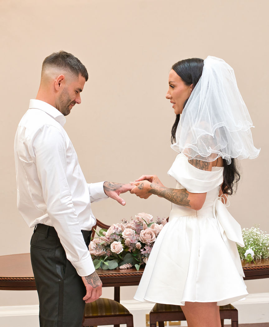 Stockport town hall wedding The bride placing the ring on her new husband 